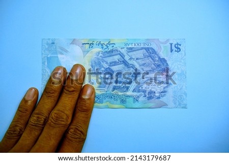 1 BND, One Brunei dollar, money concept holding by left hand businessman isolated on blue background, horizontal view    