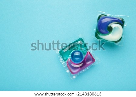 Laundry capsule detergent pods for washing clothes on blue background. Top view