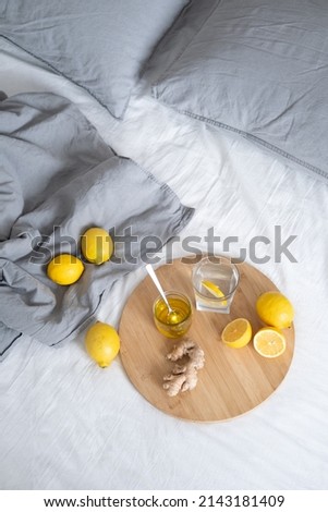 A Glass of water on a wooden serving tray with ginger root, honey and a slice of lemon on a on bed. Top view. High quality photo