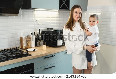 Happy mom and cheerful baby in the kitchen. Mother's love. Motherhood. The child is restless.