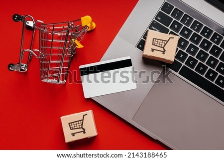 Small shopping cart, boxes and credit card on a keyboard. Top view.