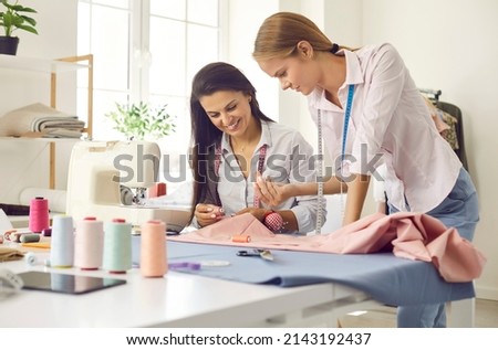 Smiling female seamstress colleagues work together sew clothing in own style workshop. Happy women tailors or designers work in fashion atelier create design garment. Dressmaking concept. Royalty-Free Stock Photo #2143192437