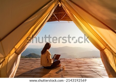 Young woman freelancer traveler working online using laptop and enjoying the beautiful nature landscape with mountain view at sunrise Royalty-Free Stock Photo #2143192569