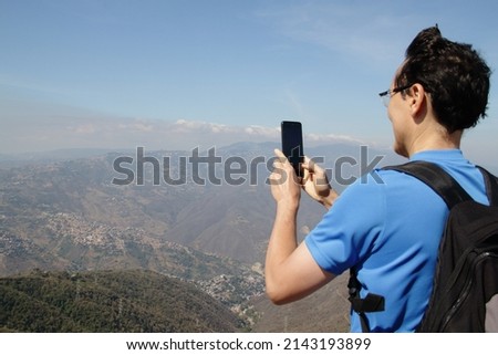 Adult man takes a picture with his cell phone during a hike in the mountains