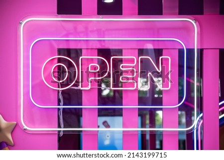 Neon light color blue Open sign on a glass window for business front of shop.