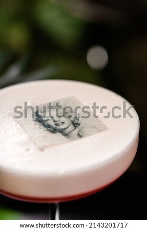 Red cocktail with white foam and the image of Marilyn Monroe