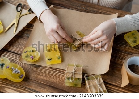 craftswoman packaging handmade soap on craft paper on table Royalty-Free Stock Photo #2143203339