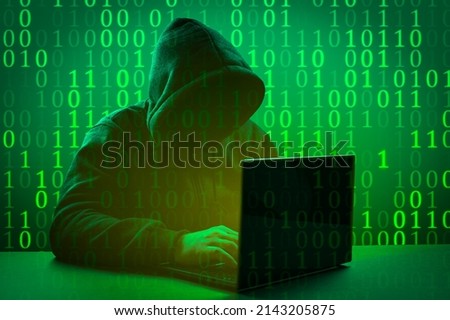 Hacker attack. Computer hacker coding on keyboard. Faceless hooded anonymous computer hacker on dark green background. Internet crime and electronic banking security Royalty-Free Stock Photo #2143205875