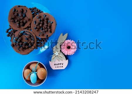 Dark Chocolate brownie cakes and Eggs with Easter bunny decoration on navy blue background. Flat lay. Copy space 