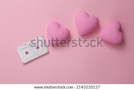 Audio cassette with hearts on a pink background. Romantic melody. Top view