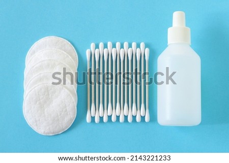 Cotton swabs and cotton pads for personal hygiene. Care product in a white bottle. White bamboo cotton buds on a blue background. Cotton buds can be used in medicine and cosmetology.