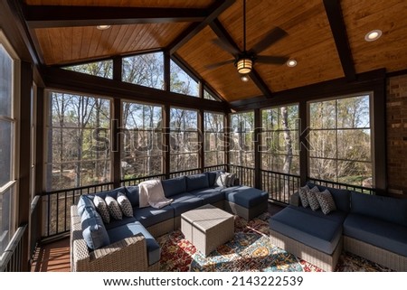 Cozy screened porch in springtime, full of blooms trees in the background.