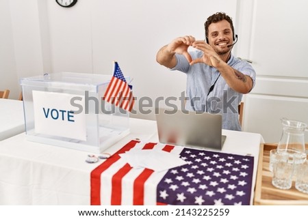 Handsome young man working at political campaign wearing operator head seat smiling in love showing heart symbol and shape with hands. romantic concept. 