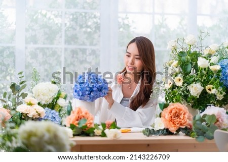 Small business. Asia Female florist smile arranging flowers in floral shop. Flower design store. happiness smiling young lady making flower vase for customers, preparing flower work from home business Royalty-Free Stock Photo #2143226709