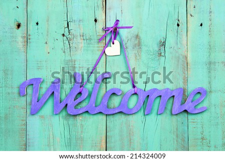 Purple welcome sign with wooden heart hanging on antique weathered green wood door