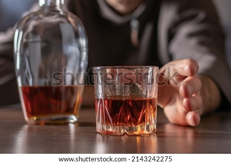 Alcoholism, alcohol addiction and people concept - male alcoholic pulls his hand to a glass of alcohol. Royalty-Free Stock Photo #2143242275