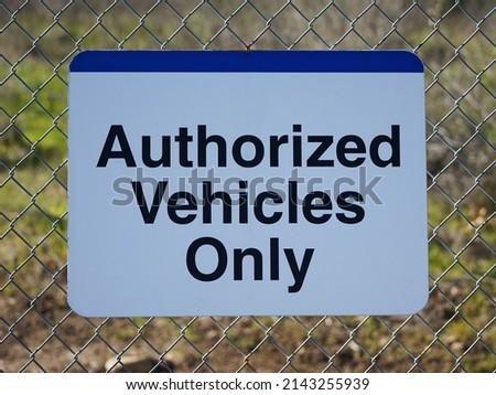 Authorized vehicles only warning sign on a chain link fence.
