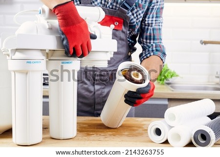 Plumber installs or change water filter. Replacement aqua filter. Repairman installing water filter cartridges in a kitchen. Installation of reverse osmosis water purification system.
 Royalty-Free Stock Photo #2143263755