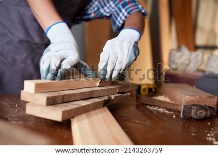 Business woman working as carpenter in a small carpentry workshop. Female carpenter working in carpentry shop with pencil drawing sign on plank.