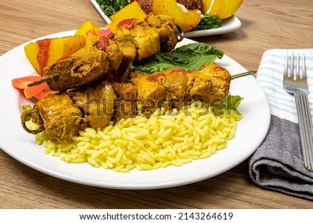 Tasty marinated Mediterranean chicken skewers or kebabs on a plate of saffron rice Royalty-Free Stock Photo #2143264619