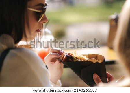 Tasty hot-dog in female's hands. Girls buy street food. Daily routines on lunch break.