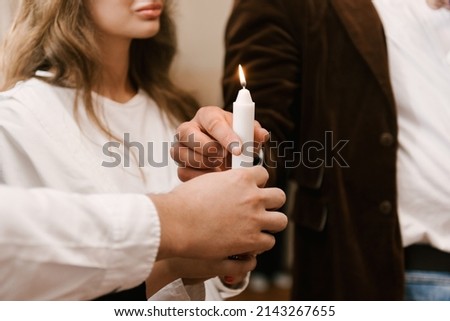 Parents hold a candle during the rite of baptism in the church Royalty-Free Stock Photo #2143267655