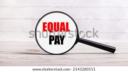 The magnifying glass stands vertically on a light background with the text EQUAL PAY