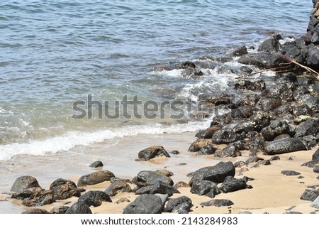 rocky shoreline with small waves crashing onto beach sand and stones Royalty-Free Stock Photo #2143284983