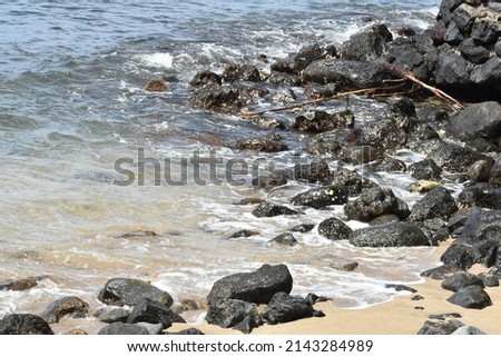 rocky shoreline with small waves crashing onto beach sand and stones