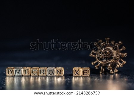 XE. A new variant of SARS-CoV-2 coronavirus. Omicron sub variant. Viral gold color on a black background Royalty-Free Stock Photo #2143286759