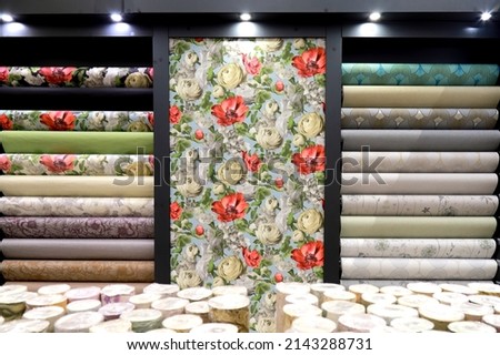 Rolls of vinyl wallpaper in building materials store. Various textures and colors as background. Wallpaper with floral pattern for wall, repair materials. Royalty-Free Stock Photo #2143288731