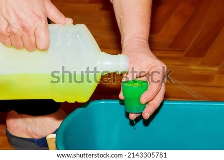 Mop your wood floor. A woman prepares a special solution for washing parquet. Housekeeping concept. Royalty-Free Stock Photo #2143305781