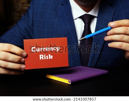 Young man holding a blank card in hands. Conceptual photo about Currency Risk with written text.
