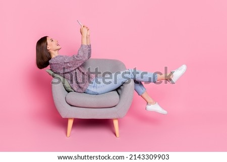 Profile side view portrait of attractive cheerful girl sitting in armchair using device isolated over pink pastel color background Royalty-Free Stock Photo #2143309903