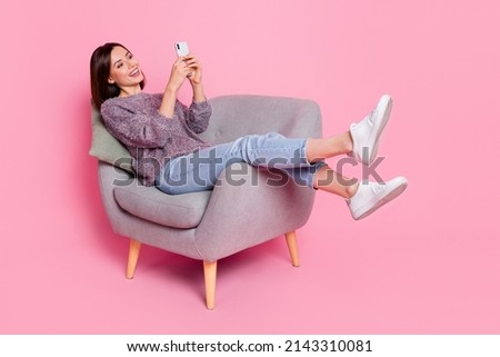 Portrait of attractive cheerful girl in armchair using device gadget smm isolated over pink pastel color background Royalty-Free Stock Photo #2143310081