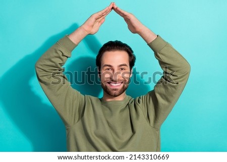 Photo of nice brunet millennial guy hands roof wear green shirt isolated on teal color background