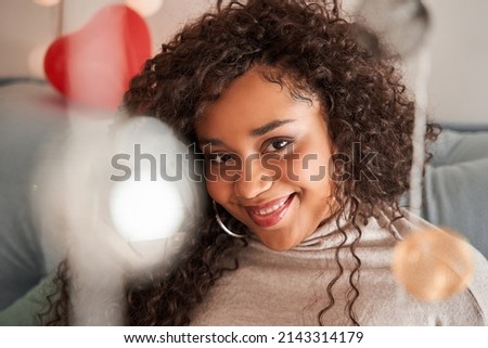 Happy multiracial woman sitting at the sofa at the domestic atmosphere and smiling to the camera
