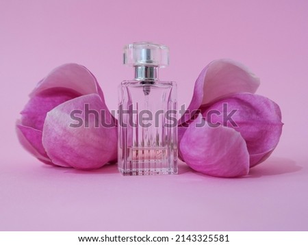 Creative layout made with elegant perfume bottle and magnolia spring flowers against pastel pink background. Spring cosmetic idea.