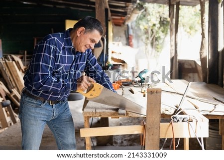 Hispanic man working with saw in his carpentry workshop-Latin Carpenter working