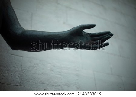 Hand of statue. Bronze hand on background of wall. Details of monument to Greek goddess.