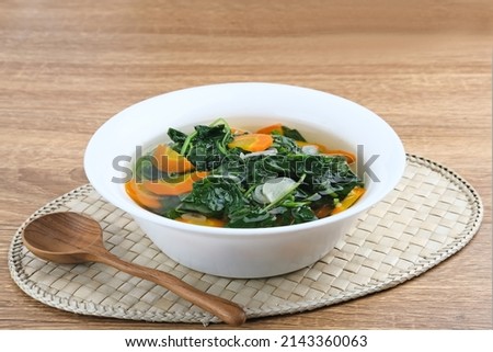 Sayur Bening Bayam, Spinach Clear Vegetable. Indonesian food of spinach, spinach soup with carrots. Served in white bowl on wooden background. 
 Royalty-Free Stock Photo #2143360063