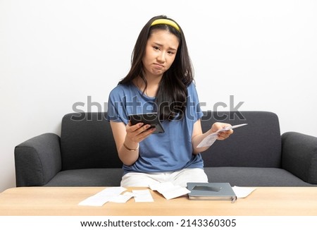 Young asian woman calculating household expenses and finance, feel frustrated at home, girl worried about debt and tax. Royalty-Free Stock Photo #2143360305