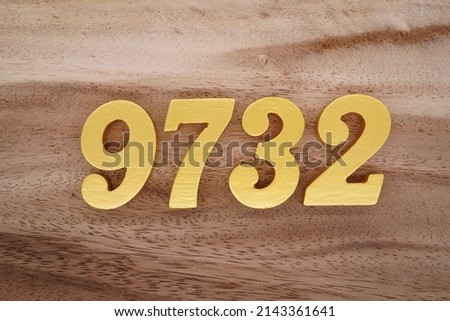 Wooden  numerals 9732 painted in gold on a dark brown and white patterned plank background.
