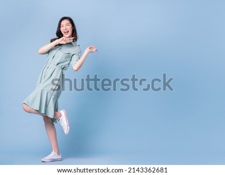 Full length image of young Asian woman wearing dress on blue background Royalty-Free Stock Photo #2143362681