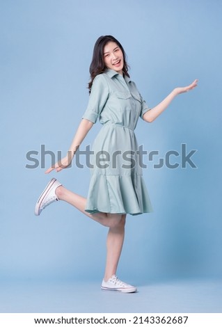 Full length image of young Asian woman wearing dress on blue background Royalty-Free Stock Photo #2143362687