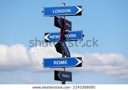 Road sign with names of capital cities isolated on blue sky background. London, New York, Rome, Paris, Rio, Berlin.