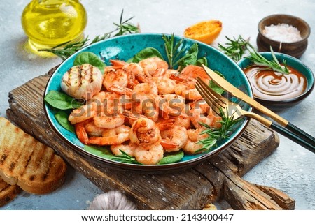 Grilled shrimp with spices and hot chili on a plate. Side view. Seafood. On a stone background.