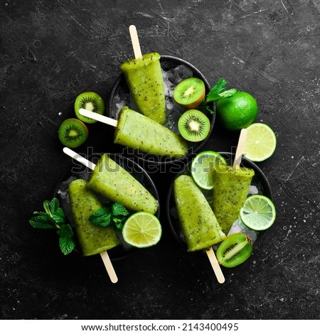 summer popsicles with lime and kiwi. On a black stone background.