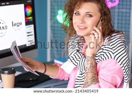 Female graphic designer talking by phone while working in office