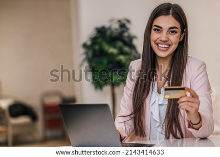 Picture of smiling young woman, happily making an online purchase with credit card.